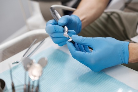 Close-up of dentists hand in blue latex gloves holding drillの写真素材
