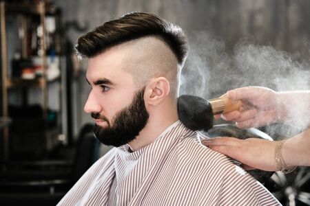 The hairdresser man in glasses cuts and shaves a beard to the young handsome man to the client in a classic suit and a baby girl. Haircut in the salon, barbershopの写真素材
