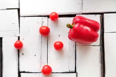 Vegetables pepper and cherry tomatoes lie on a white table of wooden pieces on a bamboo-cut board. Food, breakfast, natural products.の写真素材