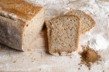 Rye bread on malt and flour, lies on the table. A whole loaf and two cut pieces of a sandwich. Near...