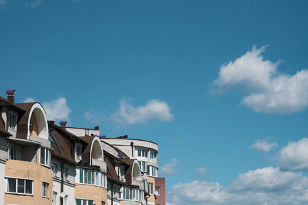 The top of a multi-storey building, a view of the roof and the sky. Brick house, windows. Urban street landscape. Beautiful photo of real estate.の写真素材