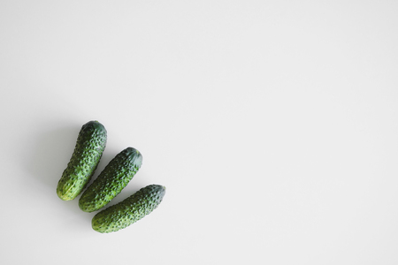 A bunch of several small gherkin cucumbers lie on a white background on a table. Top view of a close-up.の写真素材