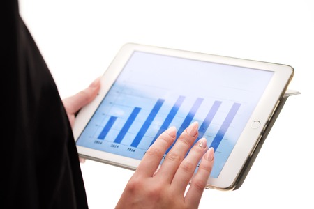 Female hands hold a tablet on which graphics are shown by years on a white background. Office and...