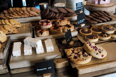 Desserts, cakes, sweets and cookies on the counter of the confectionery shop window. On the background of wooden boards and craft paper.の写真素材