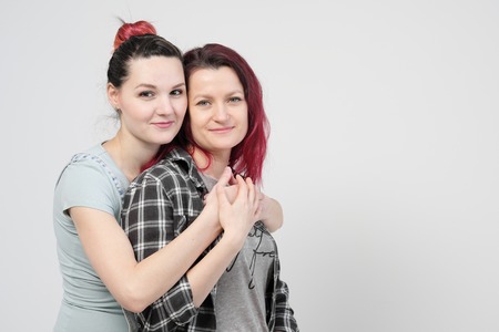 Two girls hug on a white background. Homosexual lesbian couple. Casual clothes. Same-sex marriage and tolerance to the LGBT community.の写真素材
