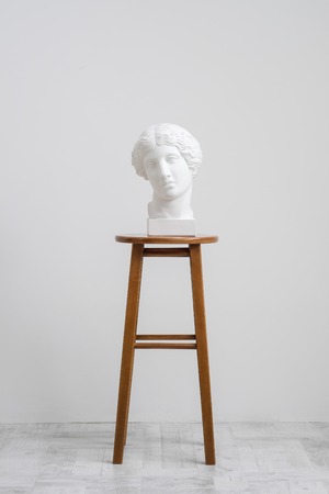 Plaster head, antique sculpture for learning to draw. Standing on a stool on a white background. Studio artist.の写真素材