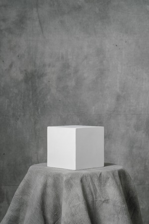 Gypsum white cube, simple geometric shape on a gray fabric art background for learning to draw. Drapery and folds.の写真素材