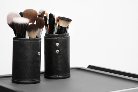 Artists make-up tools, mascara, shadows and brushes lie on a gray table, on a white background.の写真素材