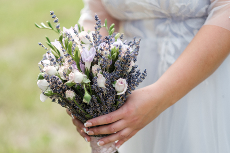 Lavender bridal bouquet in the hands of the girl against the backdrop of nature, outdoor close up.の写真素材