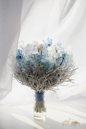 Bridal bouquet in blue white colors, closeup flowers. On a white background window.