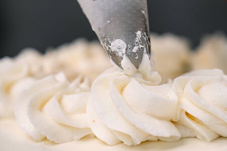 Decorating a white cake with cream from the pastry bag. Macro shot, roses.の写真素材