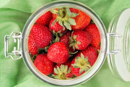Strawberries in a glass jar on green cloth. Top viewの写真素材