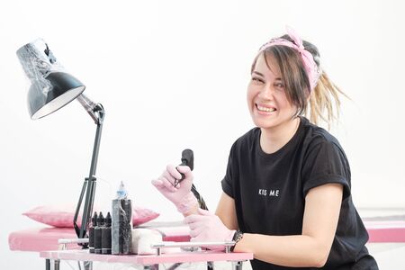Portrait of a professional tattoo master woman. Black clothes, and dreadlocks. Red, pink and white background. Place of work tattoo master. Tattoo salon for lesbians.の写真素材