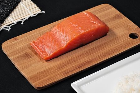 Red fish, smoked salmon on a wooden cutting board. Ingredients for rolls and sushi. The concept of...