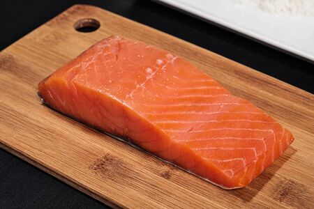 Red fish, smoked salmon on a wooden cutting board. Ingredients for rolls and sushi. The concept of...