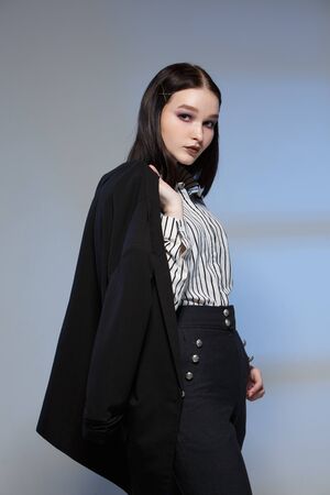 Young beautiful female fashion model in a business stylish suit on a rerom background. Holds a stack of papers and a pen. Businesswoman.の写真素材