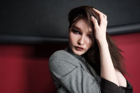 Young beautiful female fashion model in a business stylish suit on a red and black background....