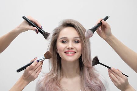 Make up salon, makeup artist work. Four hands with tassels and the face of a smiling beautiful...