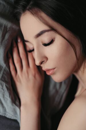 Beautiful sexy brunette woman is lying on the bed. Face close-up, beautiful brown eyes, lips and smile.の写真素材