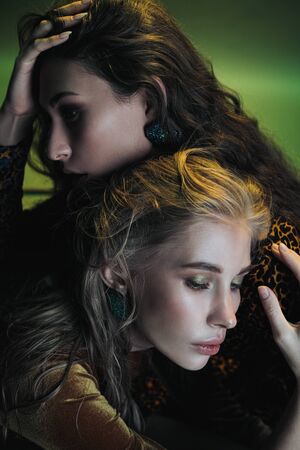 Fashion photo session in the studio. Two beautiful woman models. Blonde and brubette. Yellow leopard dress. Studio racks and flashes. Yellow and green background.の写真素材