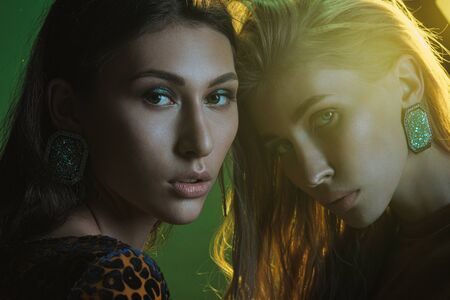 Fashion photo session in the studio. Two beautiful woman models. Blonde and brubette. Yellow leopard...