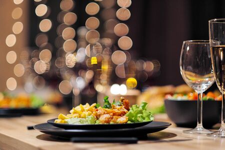 Festive table setting. Food and drinks, plates and glasses. Evening lights and candles. New Year's...