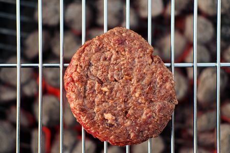 Barbecue grill. A man fries meat steaks and meatballs for hamburgers, turns the meat over with tongs. The concept of cooking meat outdoor.の写真素材