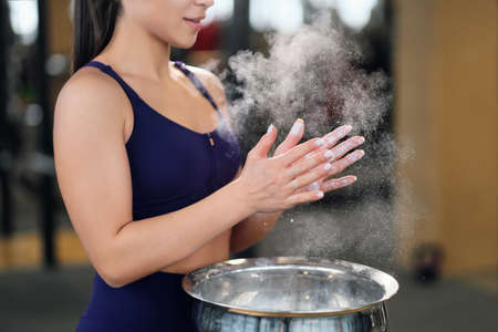 Concept fitness club. Womens powerlifting. Close-up of hands with clouds of talcum powder.
