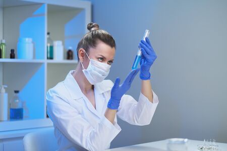 A female medical scientist works in a laboratory. Spcialist conducts experiments with fluids in test tubes, develops auccin auctin from the virus. Coronavirus covid-19.の写真素材