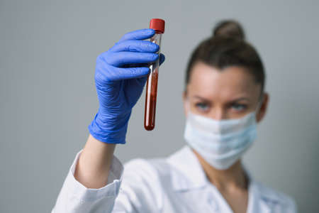 Blood test. A female medical worker holds a test tube with paciets blood. Coronavirus test.