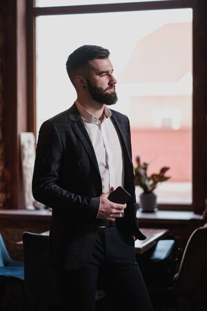 A young handsome man with a beard in a business suit in the interior of a restaurant in the loft style.の写真素材