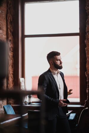 A young handsome man with a beard in a business suit in the interior of a restaurant in the loft style.の写真素材