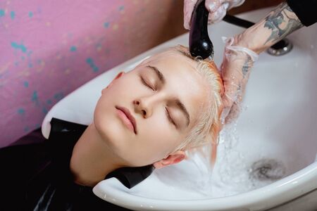 The hairdresser washes the head of a woman to a client. Colouring. The work of a colorist.の写真素材