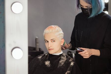 Hairdresser woman cuts her hair to a womans blonde woman. Short haircut, pixie or bob.の写真素材