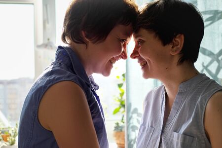 A same-sex lesbian couple poses at home. Lifestyle.