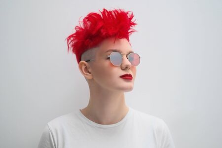 Portrait of a cool fashionable modern young girl. A short haircut with shaved temple. Dyed bright...