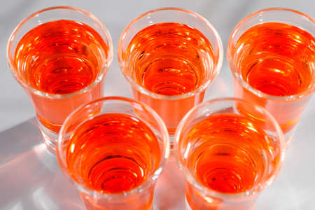 Red alcoholic shot drinks in glasses in a row on the bar count. Restaurant menu.の写真素材