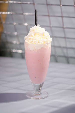 Strawberry pink milkshake with whipped cream and a tube on the bar.の写真素材