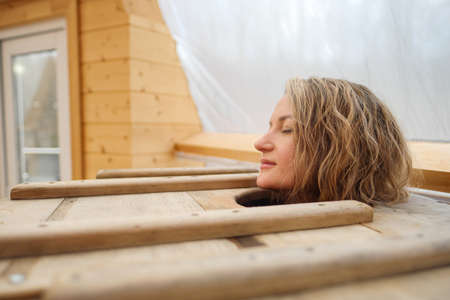 Beautiful young woman taking spa treatments in oak barrel.の写真素材