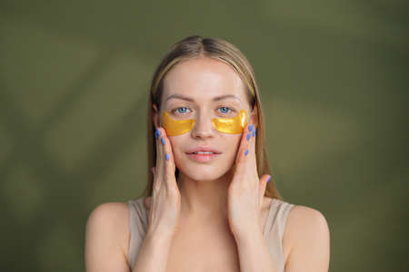 Close up of blonde caucasian girl face with natural no makeup look and white smile. Silicone under eye patches. Using skincare products from dark circles.の写真素材