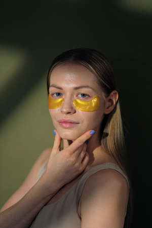 Close up of blonde caucasian girl face with natural no makeup look and white smile. Silicone under eye patches. Using skincare products from dark circles.の写真素材