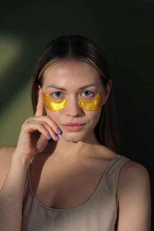 Close up of blonde caucasian girl face with natural no makeup look and white smile. Silicone under eye patches. Using skincare products from dark circles.の写真素材