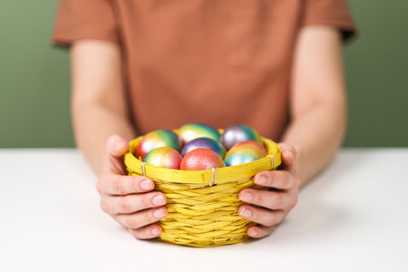A young beautiful woman in a brown t-shirt paints Easter eggs in different colors. Preparing Easter...