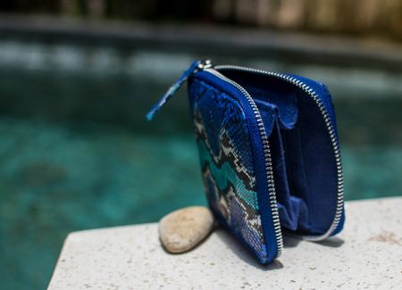 Fashion women accessories. Luxury handmade snakeskin python wallet. Top view, blue pool, light water...