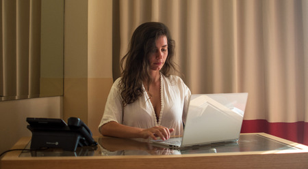 Portrait of charming talented web designer, freelancer working remotely on developing new graphics at modern netbook connected to wireless internet sitting in stylish apartment or hotel.の写真素材