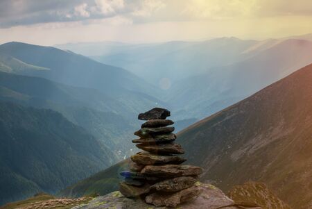 Balancing rock art. Stones balance on top of each other on a stone on top of a mountain. Ð Zen stones or a stack of zen against a background of blue mountains.の写真素材