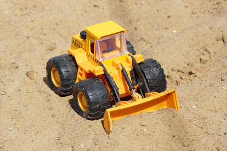 Toy yellow tractor on the sand