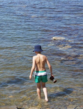 A boy in panama comes into the water. Sea.の写真素材