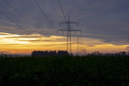 Electricity pylons power line at orange sunsetの写真素材