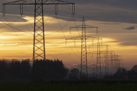Electricity pylons power line at orange sunsetの写真素材